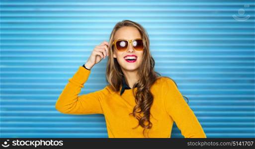 people, accessory and fashion concept - happy young woman or teen girl in casual clothes and sunglasses over blue ribbed wall background. happy young woman or teen girl in sunglasses