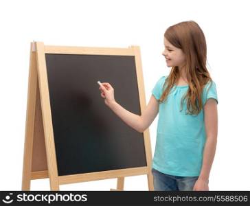 people, advertisement and education concept - happy little girl with blackboard and chalk