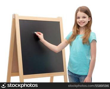 people, advertisement and education concept - happy little girl with blackboard and chalk