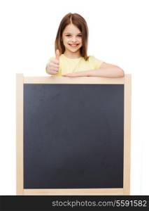 people, advertisement and education concept - happy little girl with blank blackboard showing thumbs up