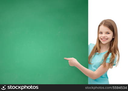 people, advertisement and sale concept - happy little girl pointing finger to blank blackboard