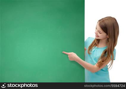 people, advertisement and sale concept - happy little girl pointing finger to blank blackboard