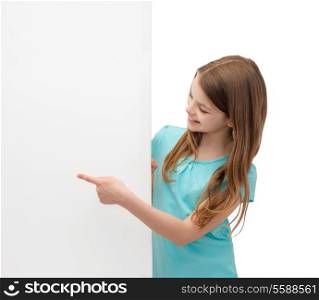 people, advertisement and sale concept - happy little girl pointing finger to blank white board