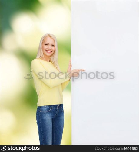 people, advertisement and sale concept - happy woman in sweater pointing finger to blank white board