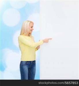 people, advertisement and sale concept - happy woman in sweater pointing finger to blank white board