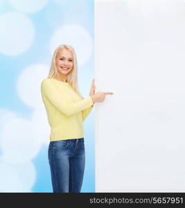 people, advertisement and sale concept - happy woman in sweater pointing finger to blank white board