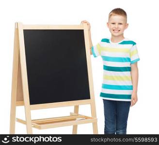 people, advertisement, childhood and education concept - happy little boy with blank blackboard