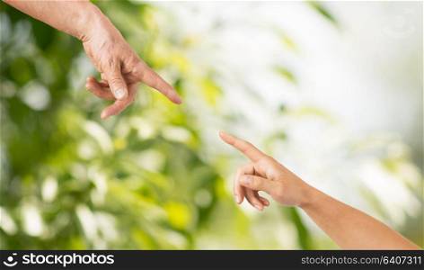 people, age and body parts concept - close up of senior and young woman hands pointing finger over green natural background. close up of senior and young woman hands