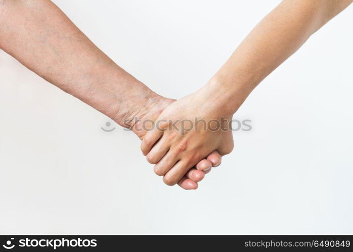 people, age and body parts concept - close up of senior and young woman holding hands. close up of senior and young woman holding hands. close up of senior and young woman holding hands