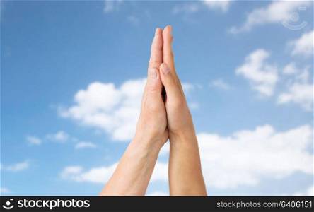 people, age and charity concept - close up of senior and young woman touching hands over blue sky and clouds background. close up of senior and young woman touching hands