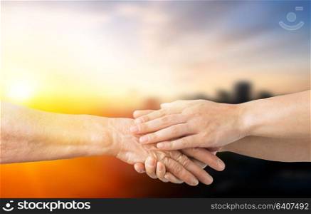 people, age and charity concept - close up of senior and young woman holding hands. close up of senior and young woman holding hands