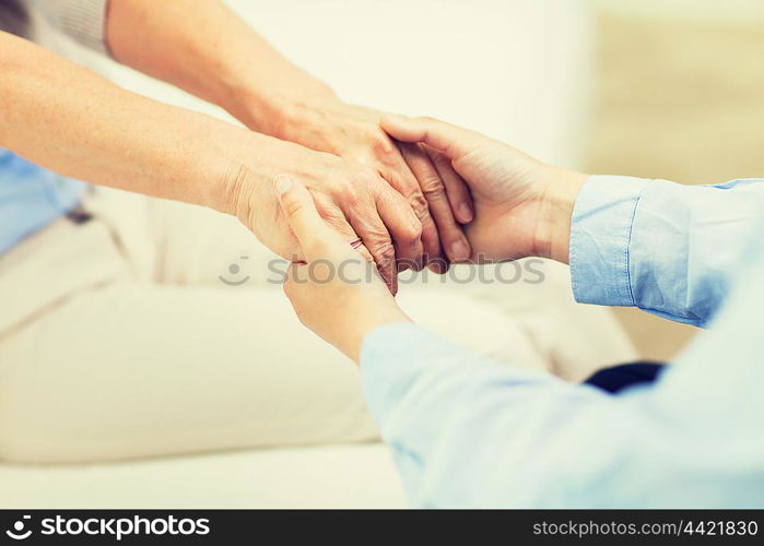 people, age, family, care and support concept - close up of senior and young woman holding hands