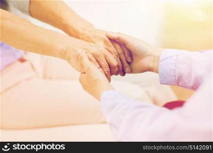 people, age, family, care and support concept - close up of senior and young woman holding hands. close up of senior and young woman hands