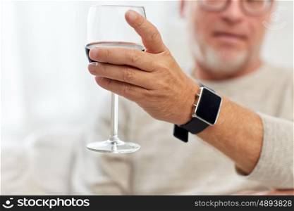 people, alcohol and drinks concept - senior man drinking red wine from glass at home