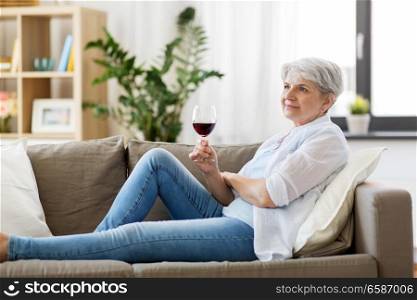 people, alcohol and leisure concept - senior woman with glass of red wine at home. senior woman with glass of red wine at home
