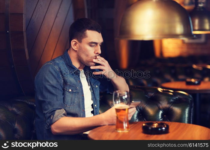 people and bad habits concept - man drinking beer and smoking cigarette at bar or pub. man drinking beer and smoking cigarette at bar