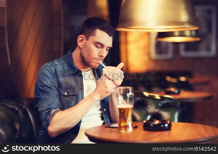 people and bad habits concept - man drinking beer and smoking cigarette at bar or pub. man drinking beer and smoking cigarette at bar