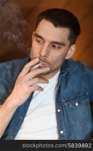 people and bad habits concept - young man smoking cigarette at bar. young man smoking cigarette at bar