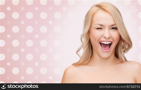 people and beauty concept - beautiful smiling young woman winking one eye over pink and white polka dot pattern background