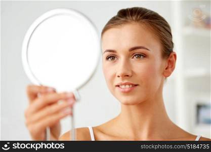 people and beauty concept - beautiful woman looking to mirror at home. beautiful woman looking to mirror at home