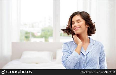 people and bedtime concept - happy young woman in pajama whipping her hair over background. happy young woman in pajama over bedroom