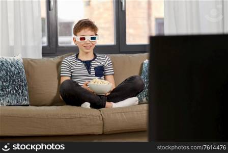 people and childhood concept - happy smiling boy in 3d movie glasses eating popcorn and watching tv at home. boy in 3d movie glasses and watching tv at home