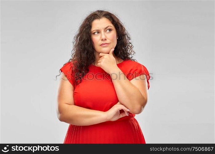 people and choice concept - serious woman in red dress thinking over grey background. serious woman in red dress thinking