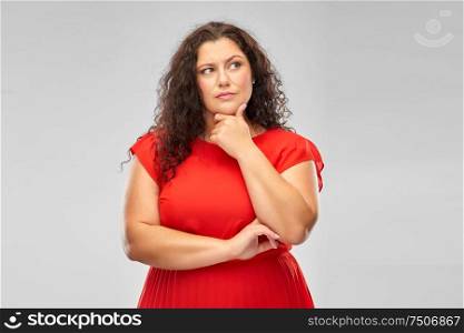 people and choice concept - serious woman in red dress thinking over grey background. serious woman in red dress thinking
