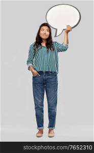 people and communication concept - confused asian young woman holding big blank speech bubble over grey background. confused asian woman holding speech bubble