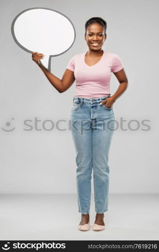 people and communication concept - happy african american young woman holding big blank speech bubble over grey background. happy african american woman holding speech bubble