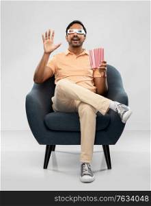 people and concept - happy smiling young indian man in 3d glasses eating popcorn and watching movie sitting in chair over grey background. happy man in 3d movie glasses eating popcorn