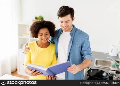 people and cooking concept - happy couple reading cookbook at home kitchen. happy couple with cooking book at home kitchen