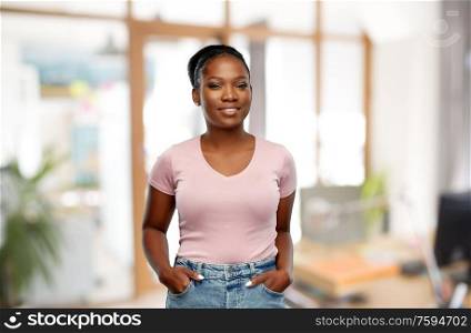 people and corporate concept - happy smiling african american young woman over office background. happy african american woman over office