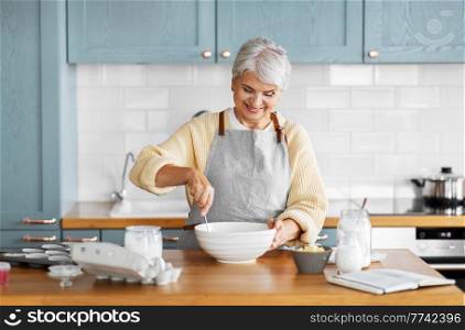 people and culinary concept - happy smiling woman cooking food on kitchen at home. happy woman cooking food on kitchen at home