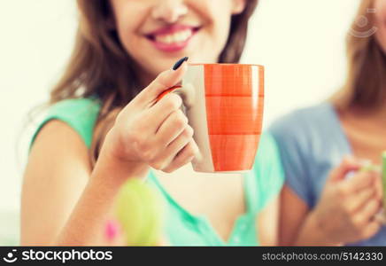 people and drinks concept - close up of happy woman or teen girl drinking tea from cup. happy woman or teen girl drinking tea from cup