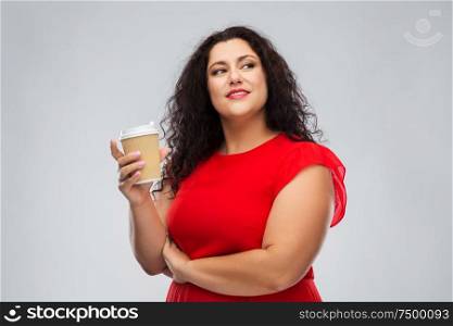 people and drinks concept - portrait of happy woman in red dress holding takeaway coffee cup over grey background. woman in red dress holding takeaway coffee cup