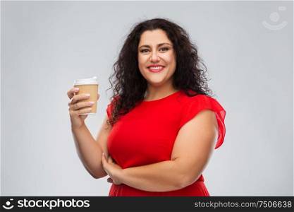 people and drinks concept - portrait of happy woman in red dress holding takeaway coffee cup over grey background. woman in red dress holding takeaway coffee cup