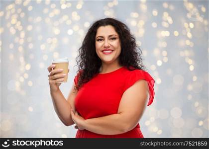 people and drinks concept - portrait of happy woman in red dress holding takeaway coffee cup over festive lights background. woman in red dress holding takeaway coffee cup
