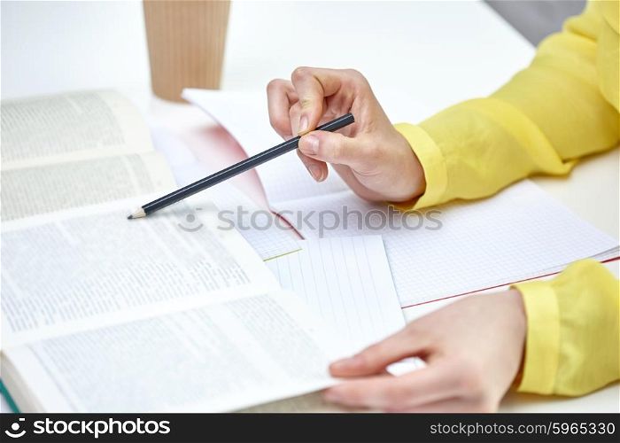 people and education concept - close up of female hands pointing pencil to book or textbook at school. close up of female hands with book and notebooks