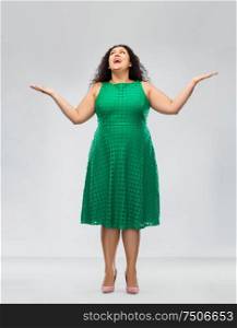 people and emotion concept - happy amazed woman in green dress looking up over grey background. happy smiling woman in green dress looking up