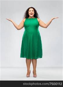 people and emotion concept - happy amazed woman in green dress over grey background. happy smiling woman in green dress