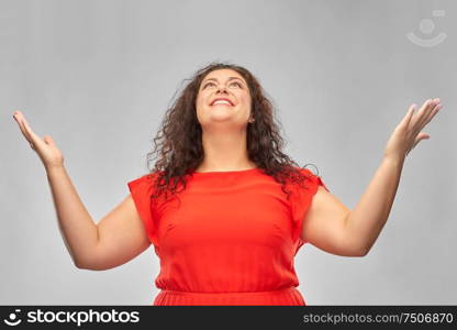 people and emotion concept - happy amazed woman in red dress looking up over grey background. happy smiling woman in red dress looking up