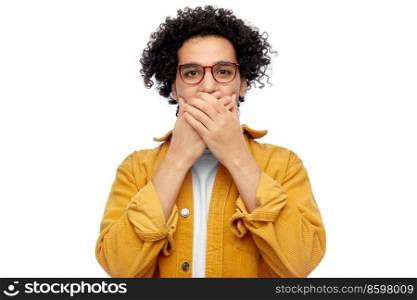 people and emotion concept - man in glasses and yellow jacket covering mouth by hands over white background. man in glasses and jacket covering mouth by hands