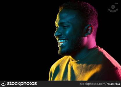 people and ethnicity concept - portrait of happy smiling young african american man over black background. young african american man over black background