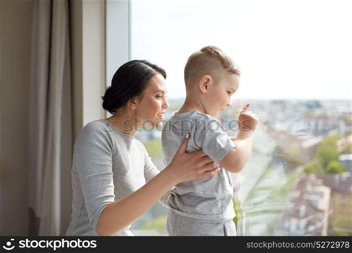 people and family concept - happy mother and little son looking through window at home. mother and son looking through window at home