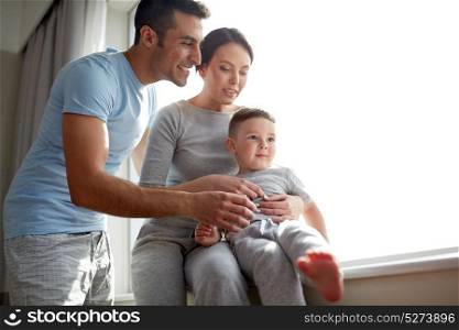 people and family concept - happy mother, father and little son at window. happy family at window