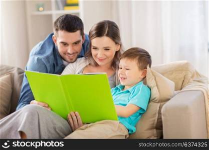 people and family concept - happy mother, father and little son reading book on sofa at home. happy family reading book at home