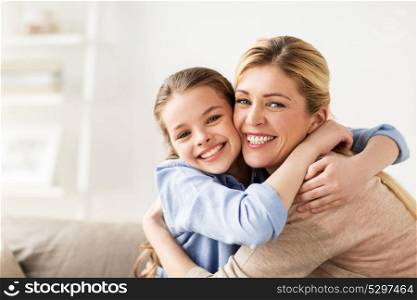people and family concept - happy smiling girl with mother hugging on sofa at home. happy smiling family hugging on sofa at home