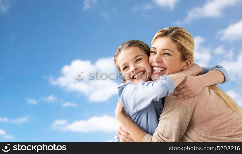 people and family concept - happy smiling girl with mother hugging over blue sky and clouds background. happy family of girl and mother hugging over sky