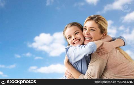 people and family concept - happy smiling girl with mother hugging over blue sky and clouds background. happy family of girl and mother hugging over sky